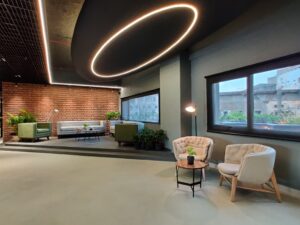 Lounge seating area with brick wall and greenery inside Alembic City, Vadodara